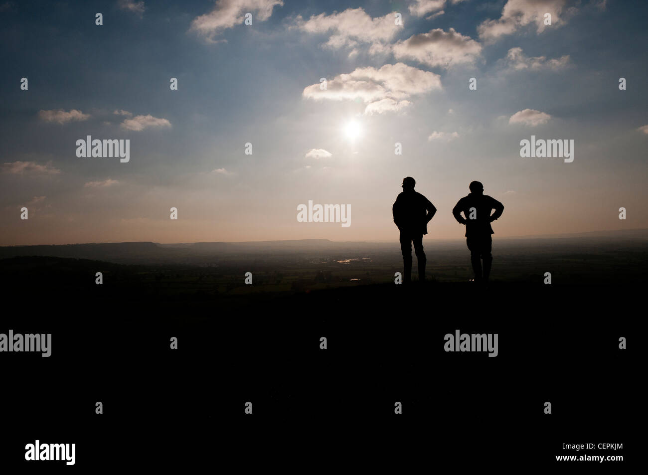 Silhouette von zwei Wanderer auf dem Hügel, genießen die Aussicht, Haresfield Leuchtfeuer, in der Nähe von Stroud, Gloucestershire, UK Stockfoto