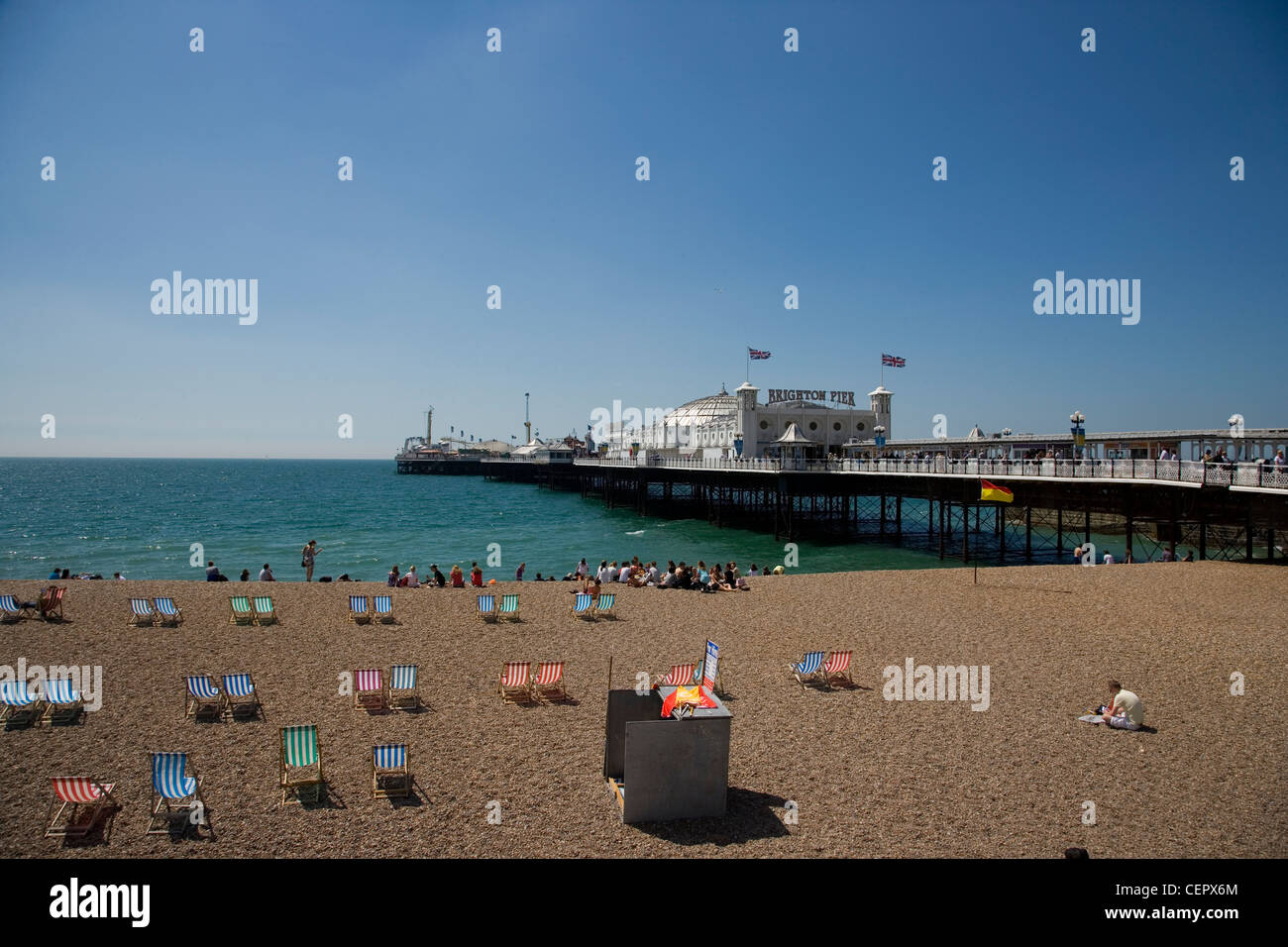 Menschen und Liegestühle am Strand am Pier von Brighton. Stockfoto