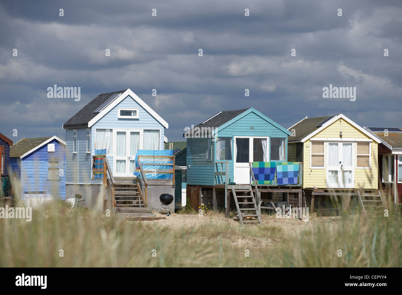 Ein Blick durch lange Grashalme in Richtung Strandhütten am Strand von Mudeford, zwei Meilen von Christchurch. Stockfoto