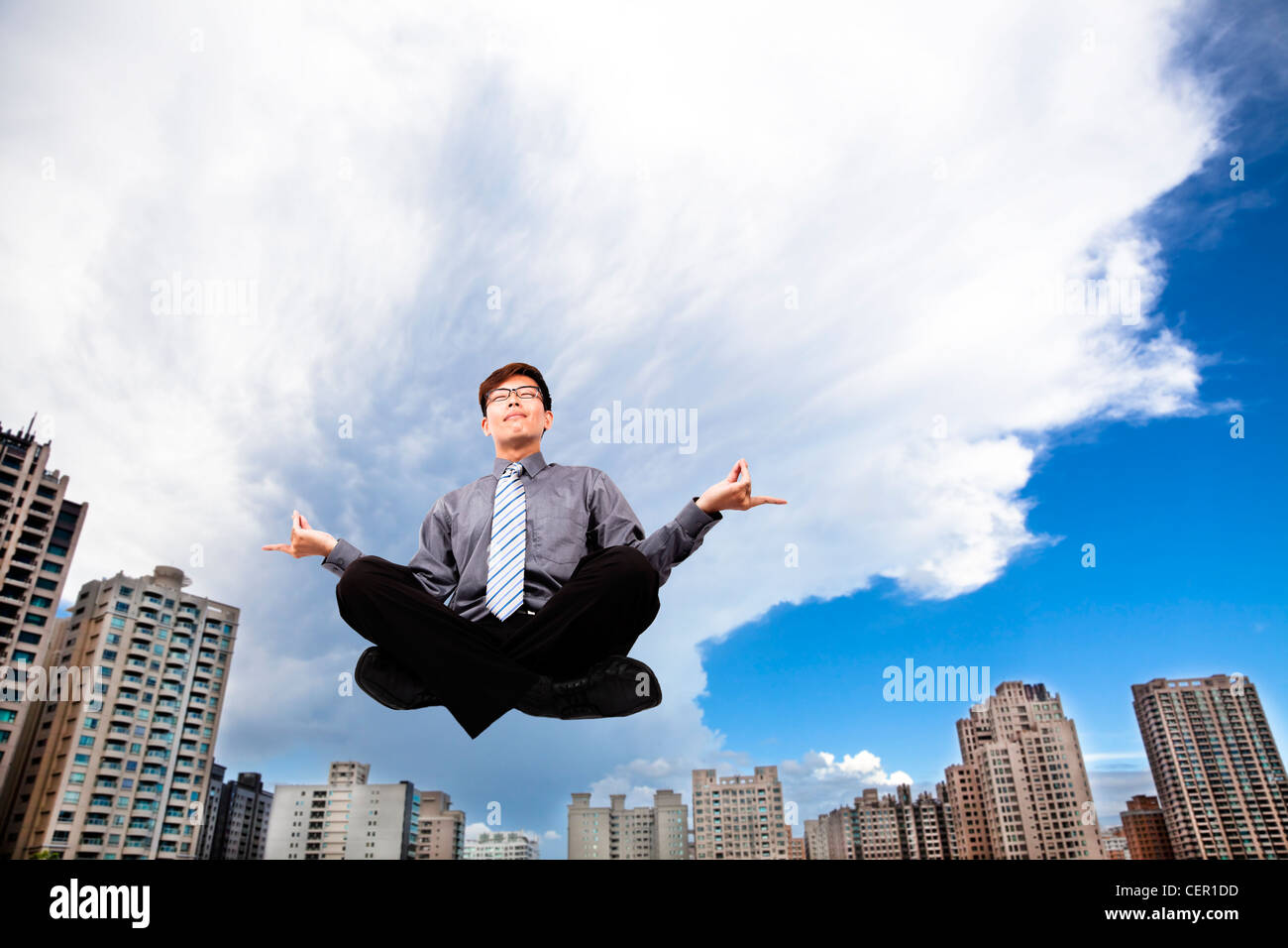 Geschäftsmann, meditierend in der Luft vor dem modernen Gebäude Stockfoto