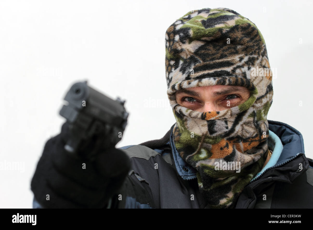 Terrorist mit Maske mit dem Ziel mit seiner Pistole auf weiß Stockfoto