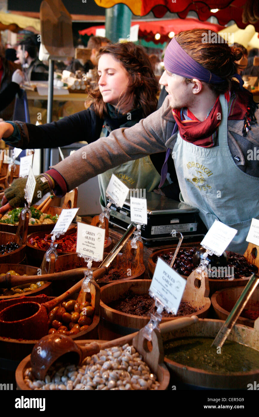 Mitarbeitende, die Dienstleistungen von einer Olive stall im Borough Market. Stockfoto