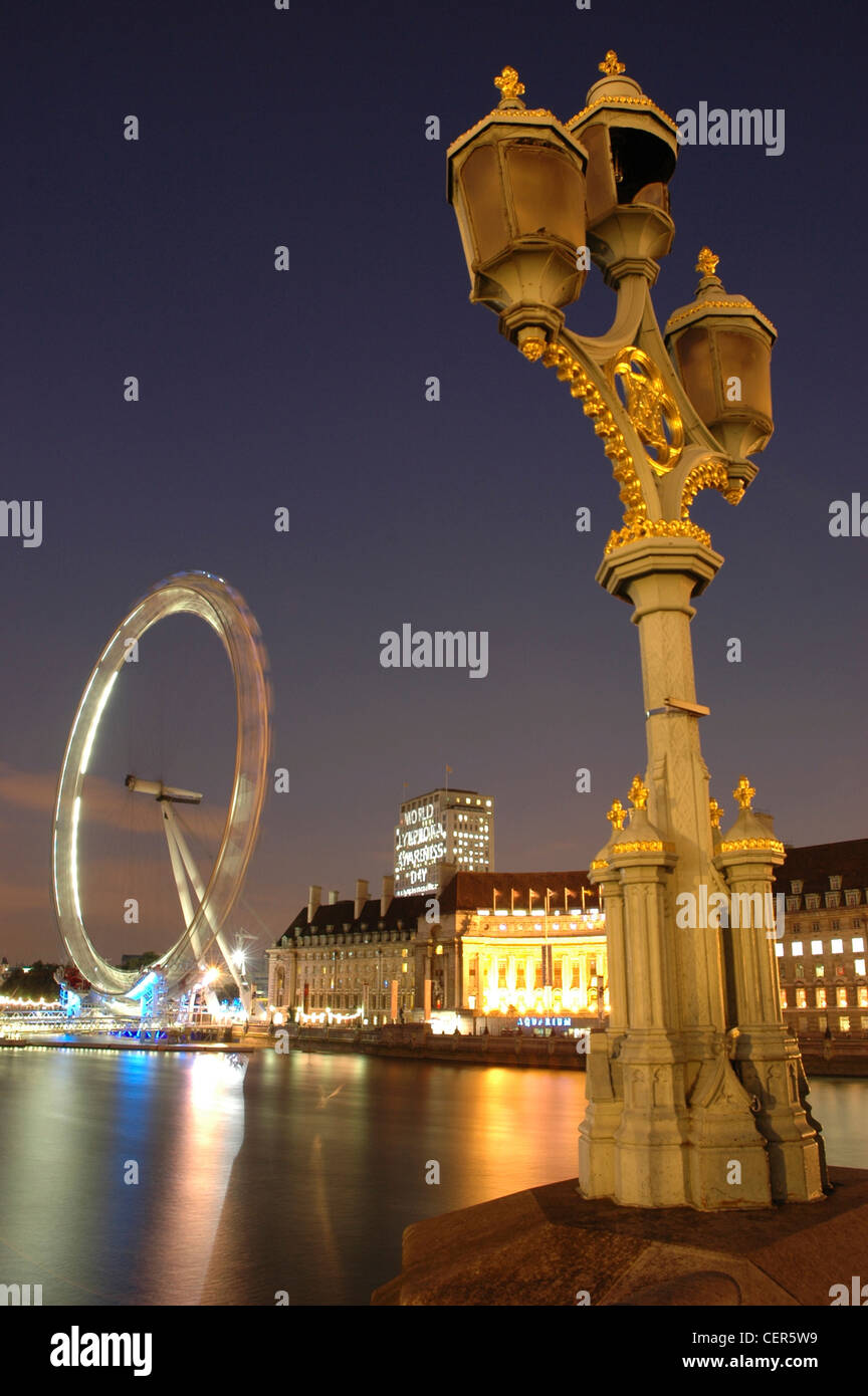 Das London Eye in der Nacht von Westminster Bridge gesehen und umrahmt von einer traditionellen Straßenlaterne. Stockfoto