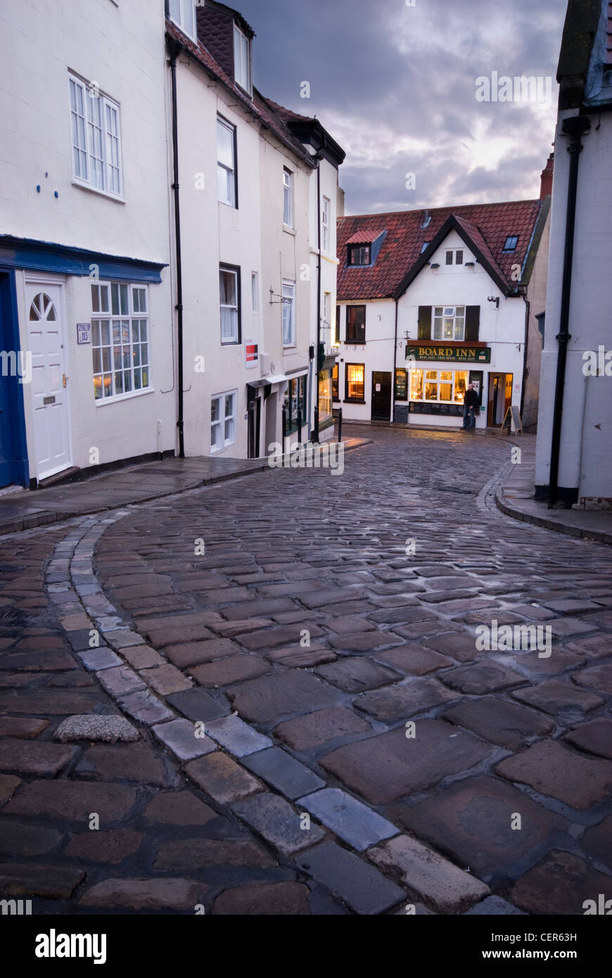 Traditionelle gepflasterten Straße Wicklung gegenüber dem Vorstand Inn Pub in Whitby. Stockfoto