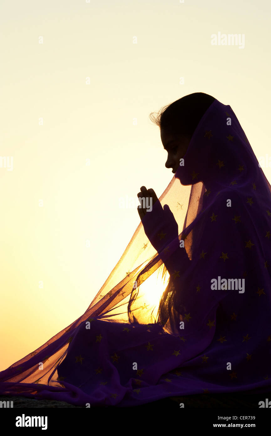 Indische Teenager-Mädchen beten bei Sonnenuntergang mit einem Stern Schleier bedeckt. Silhouette. Indien Stockfoto