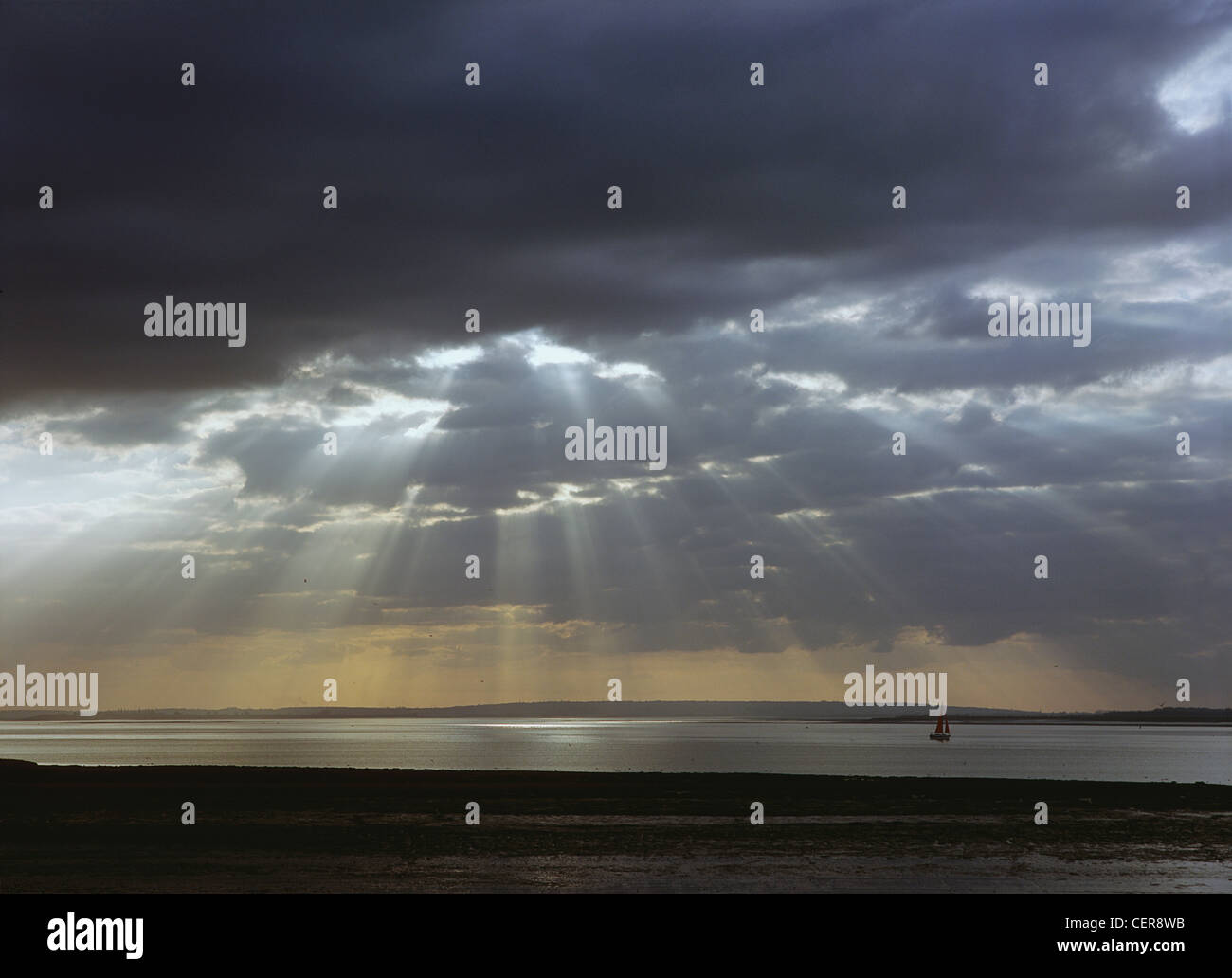 Sonnenlicht-streaming durch dunkle Gewitterwolken über dem Fluss Blackwater in der Nähe von Bradwell Waterside in Essex. Stockfoto