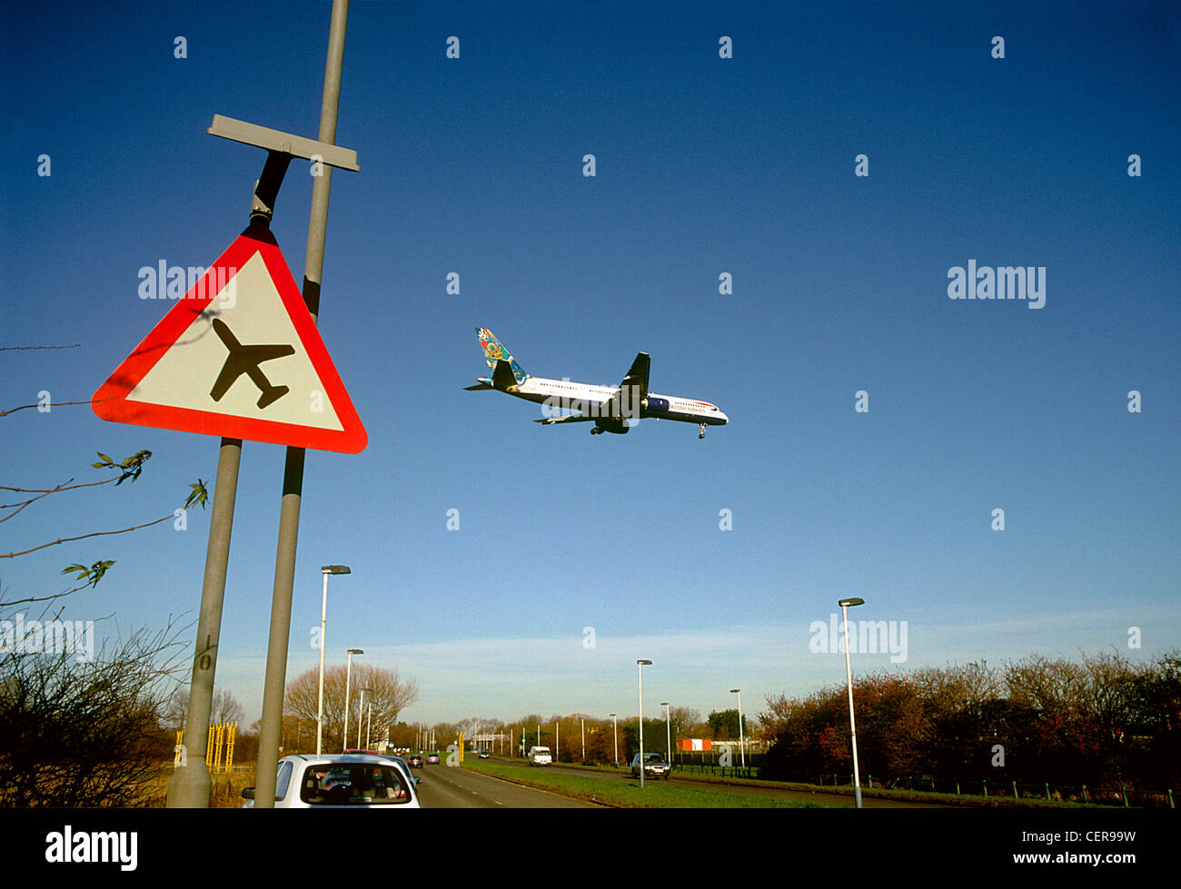 Ein Flugzeug landen am Flughafen Heathrow über eine niedrig fliegende Flugzeug Schild am Straßenrand vorbei kommen. Stockfoto