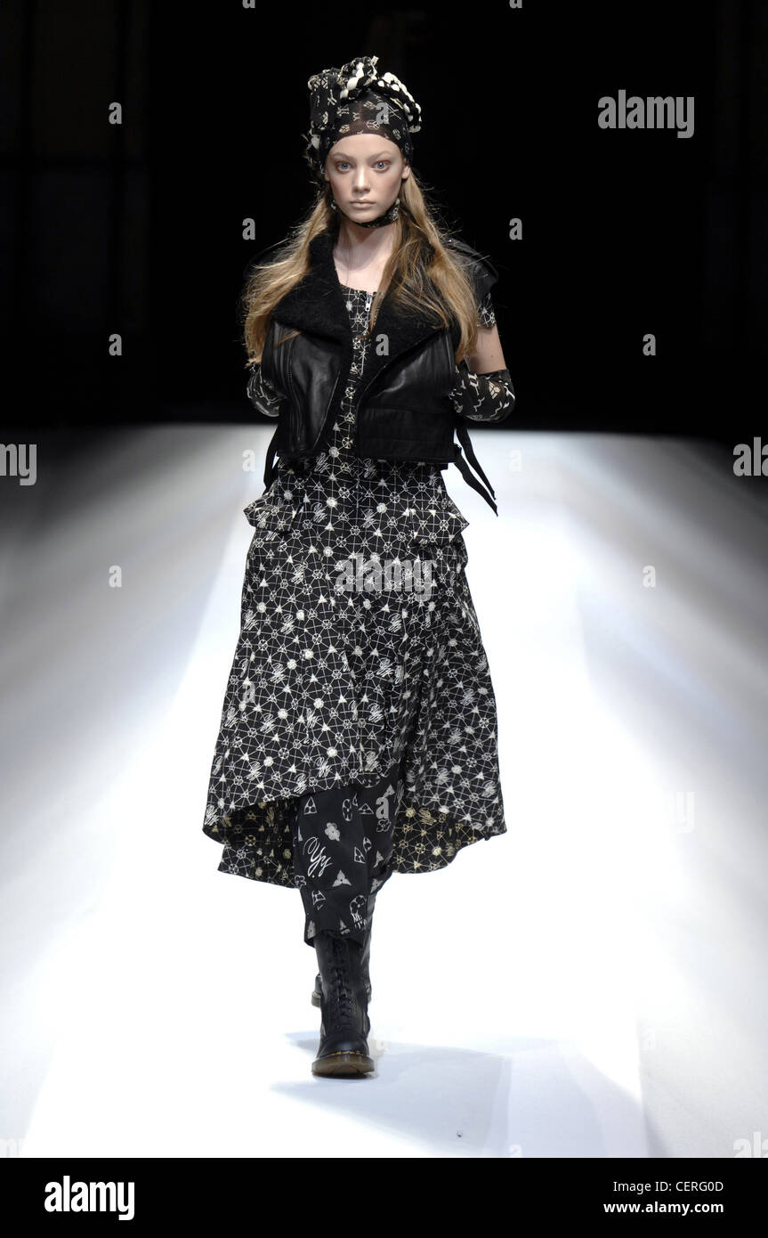 Modell mit schwarzen und weißen Muster Kleid über Leggins, Stiefel, Schnürschuh beschnitten schwarze Weste, Kopftuch Stockfoto
