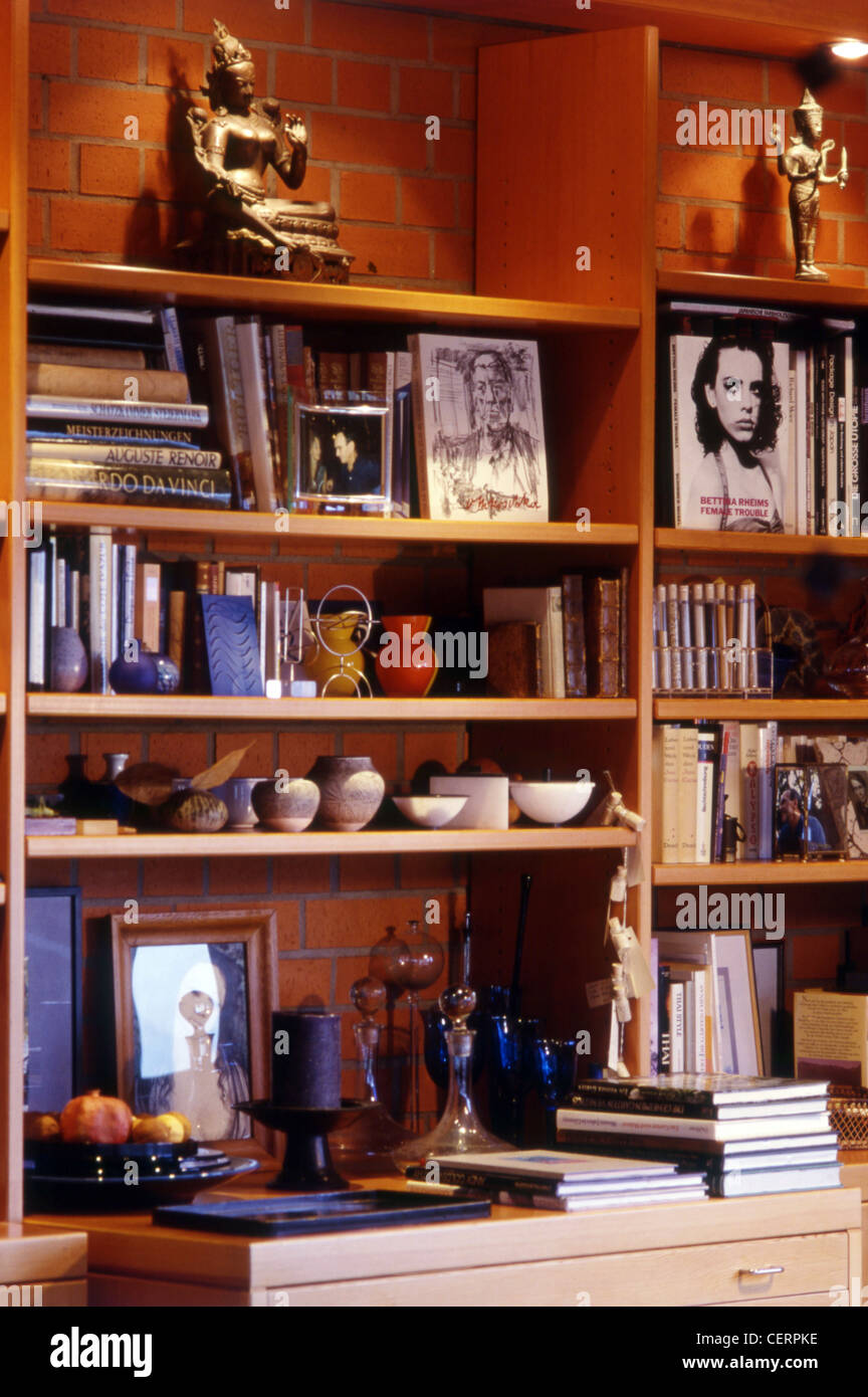 Blick auf Holzregale mit Auswahl an Bücher, Vasen und Schmuck, Mauerwerk hinter Regalen Stockfoto