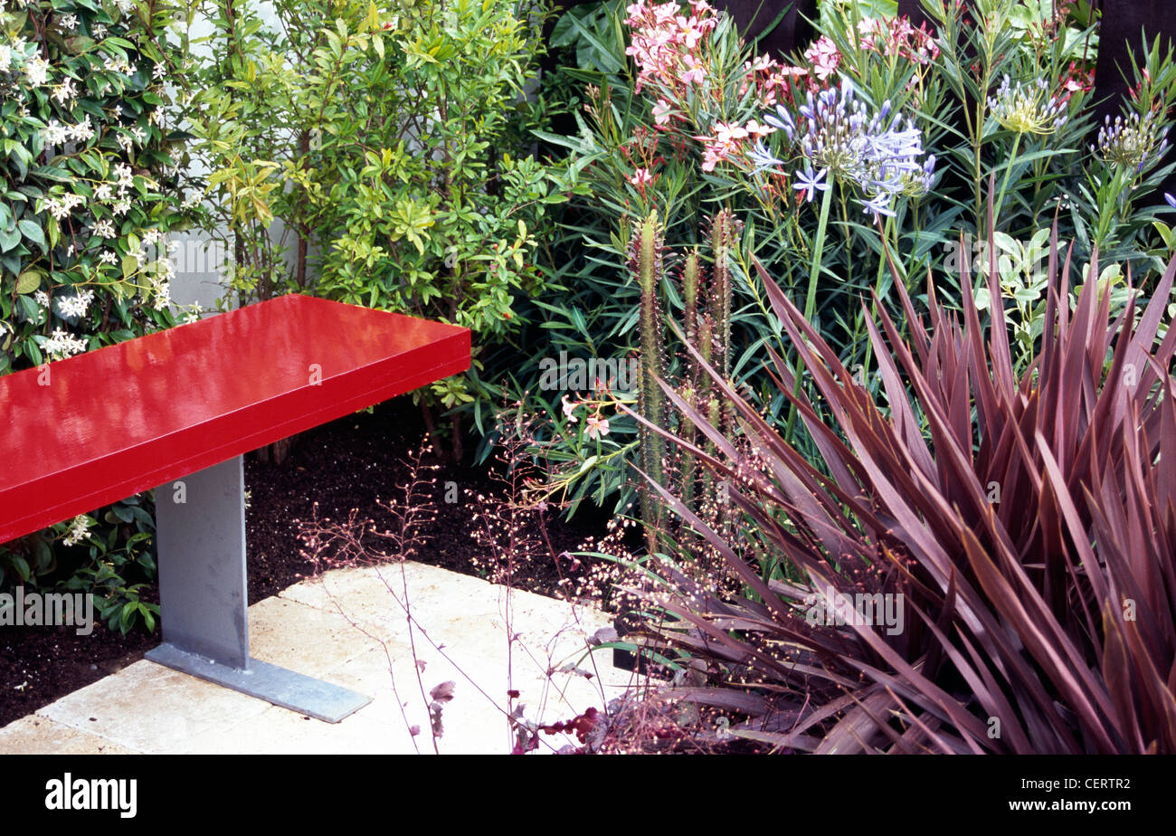 Moderne rote Bank mit Phorium, Agapanthus, Oleander Amd Kakteen Stockfoto