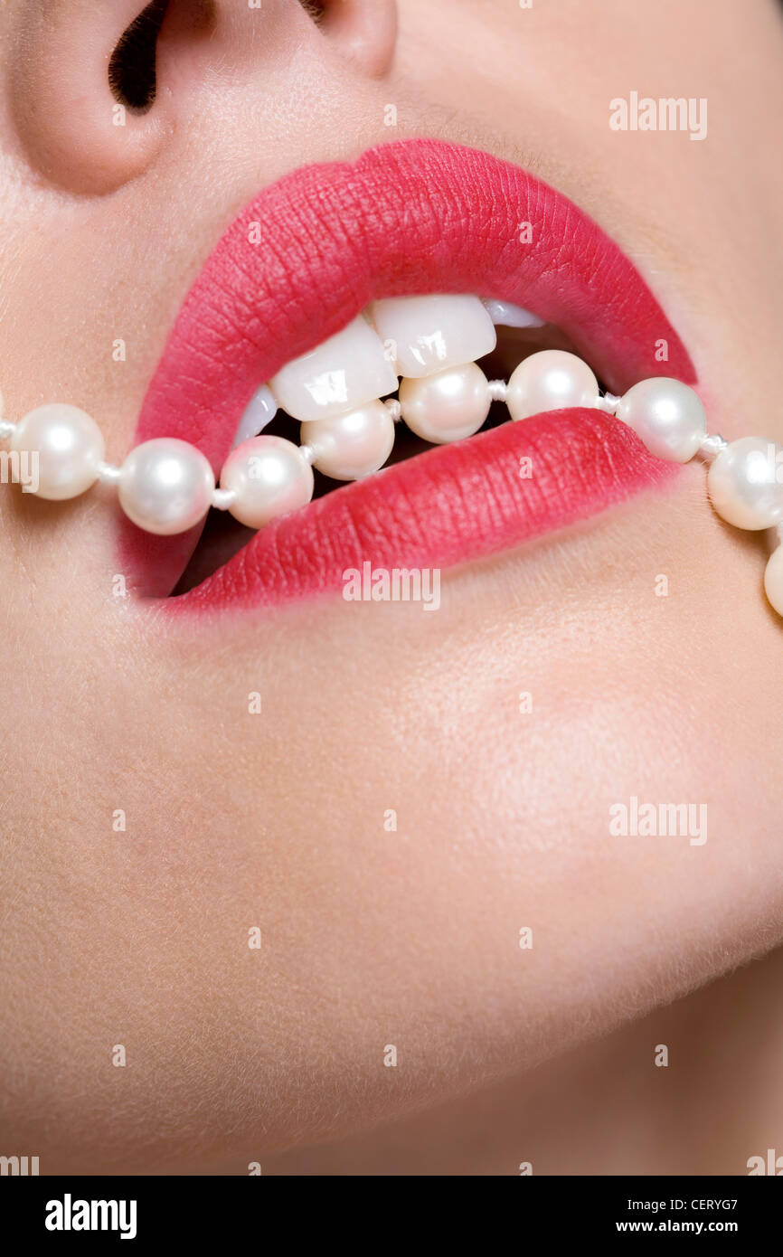 Weibchen mit tief rosa Lippenstift, beißen eine Zeichenkette der Perlen Stockfoto