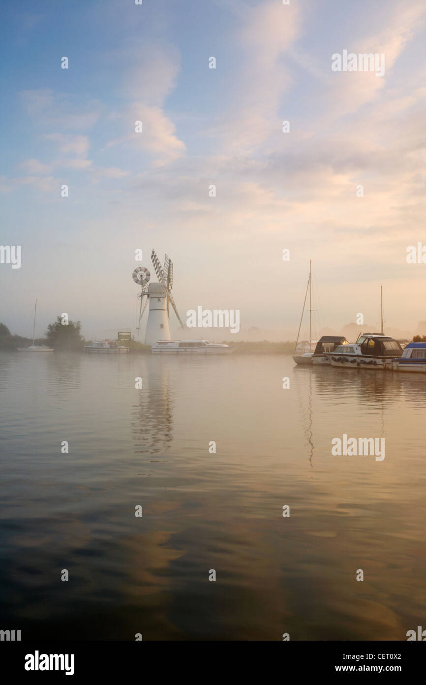 Eine neblige Sicht über das Wasser zu Thurne Mill bei Sonnenaufgang. Stockfoto