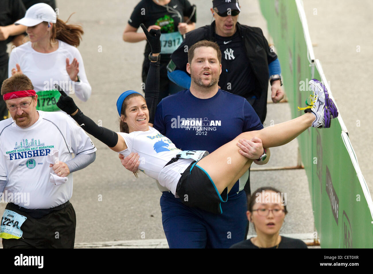 Anglo Mann trägt Frau über die Ziellinie beim Austin-Marathon in der Innenstadt von Austin Texas. Stockfoto