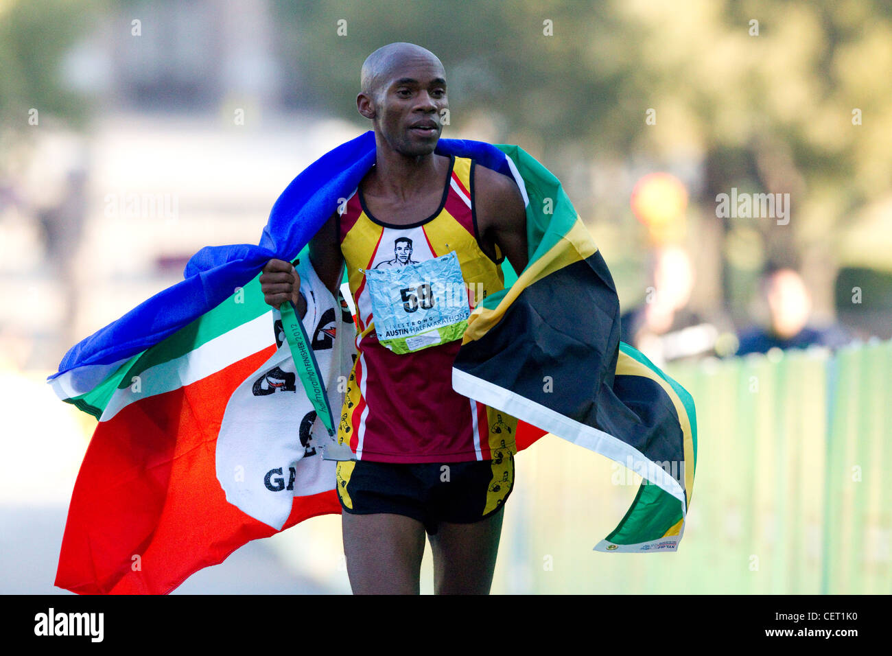 Männliche Sportler aus Südafrika trägt Flaggen nach dem Gewinn der Männer halb-Marathon Rennen in Austin, Texas Stockfoto