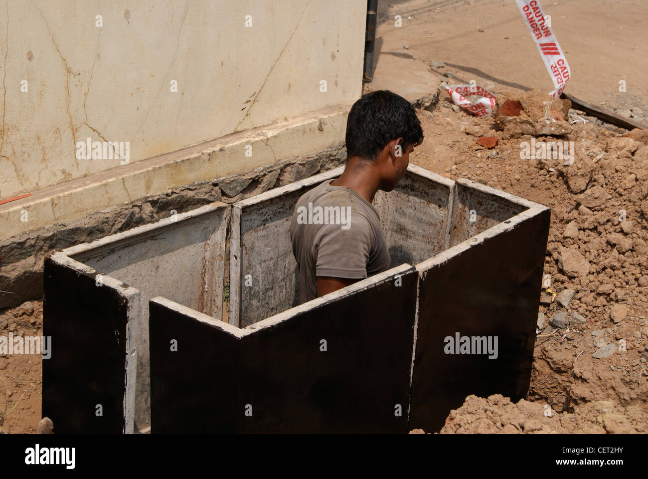 Mann, der auf unterirdische Kabel Laying.Working Mann am Straßenrand liegen Kabel arbeitet. Szene von Trivandrum City von Kerala, Indien Stockfoto