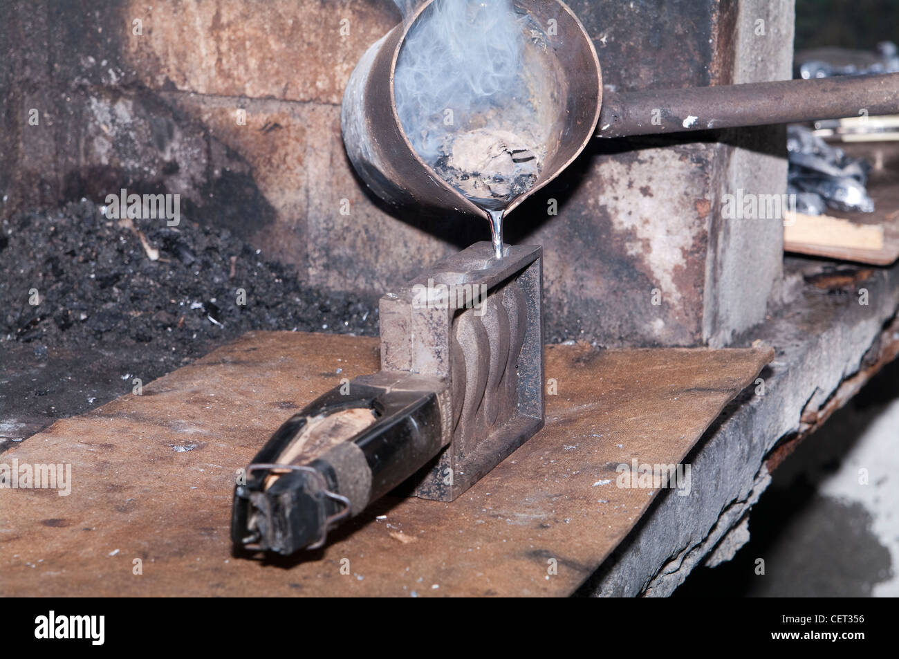 Schmelzendes Blei, um selbstgemachte Sinker zum Angeln herzustellen. Geschmolzenes Metall wird aus einer Pfanne in eine quadratische Gussform in einer Metallwerkstatt gegossen. Stockfoto