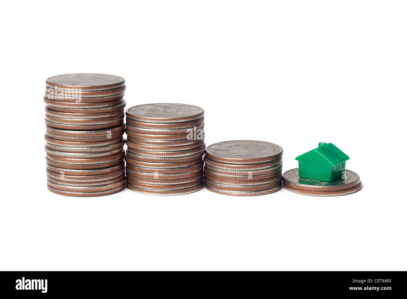 Spielzeug-Haus und Haufen von Münzen für Downgrade auf ein kleineres Haus Stockfoto