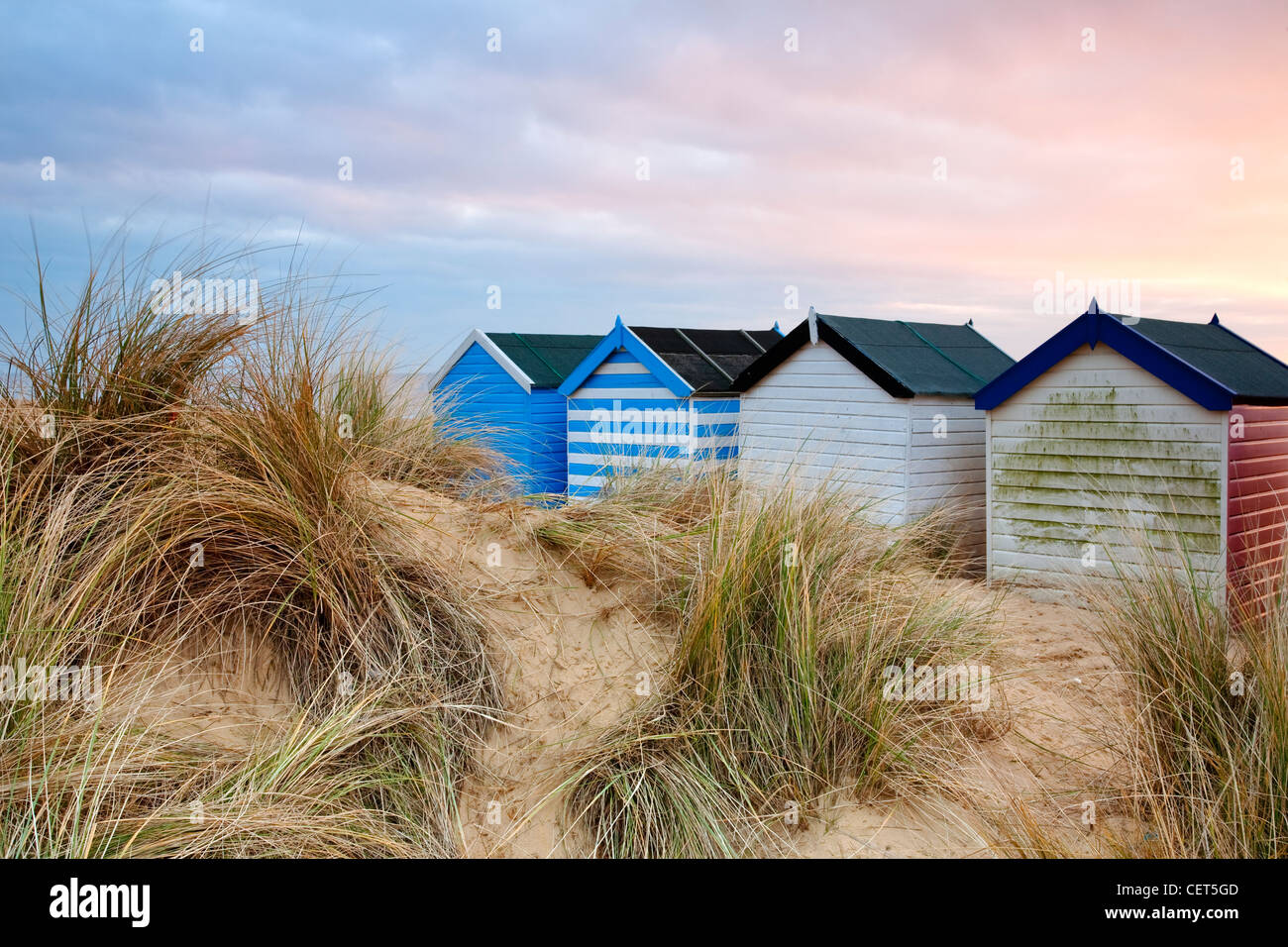 Morgendämmerung über Sanddünen und bunten Strandhäuschen entlang der Strandpromenade in Southwold an der Küste von Suffolk. Stockfoto