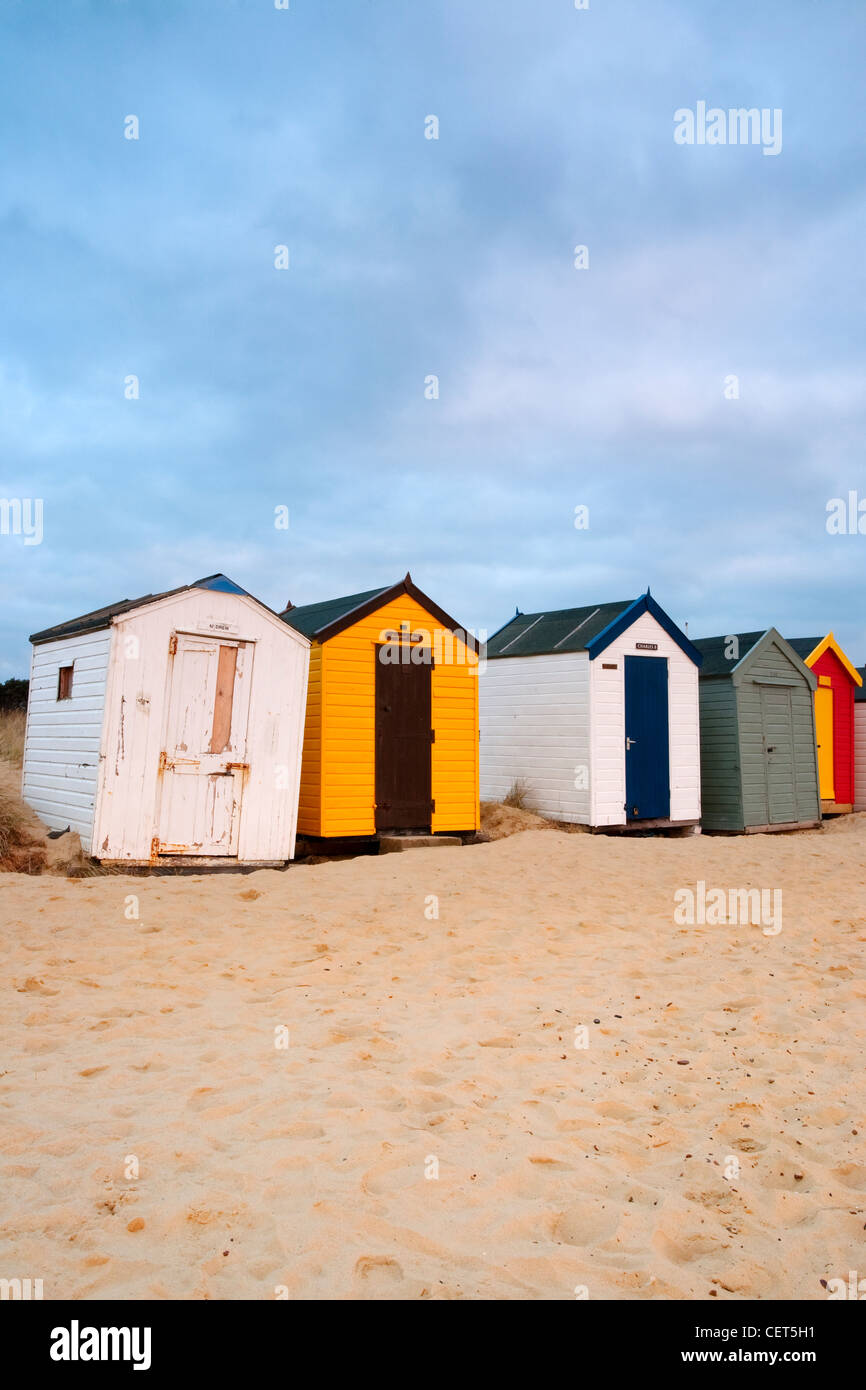 Eine Reihe von bunten Strandhäuschen am Sandstrand in Southwold an der Küste von Suffolk im Morgengrauen. Stockfoto