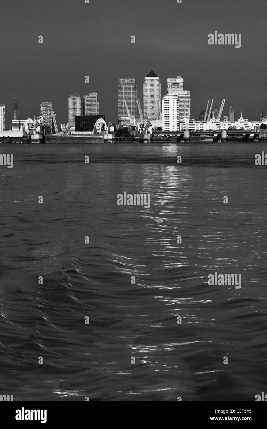 Canary Wharf, The Millenium Dome und der Thames Barrier in schwarz / weiß genommen von einem Boot auf der Themse Stockfoto