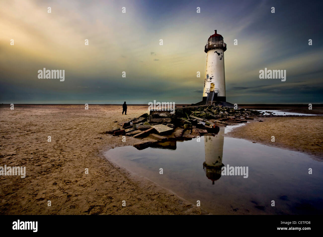 Ein Passant durch neben Talacre Leuchtturm am Strand entlang spazieren. Stockfoto