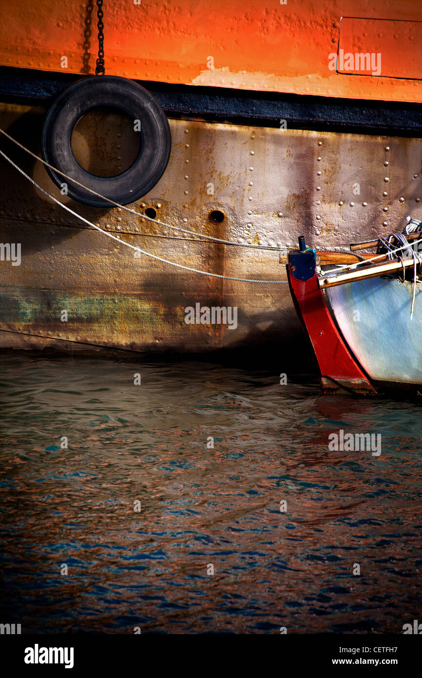 Zum Jahresende ein kleines Boot festgemacht an der Seite eines großen Schiffes im Hafen von Maryport. Stockfoto