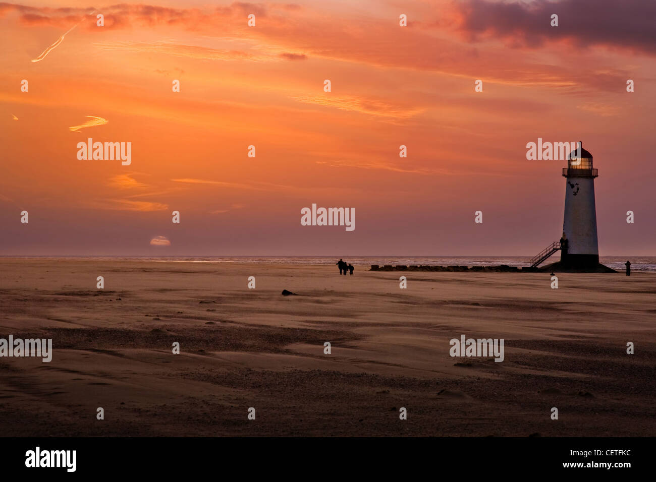Menschen zu Fuß am Strand neben Talacre Leuchtturm in der Abenddämmerung. Stockfoto