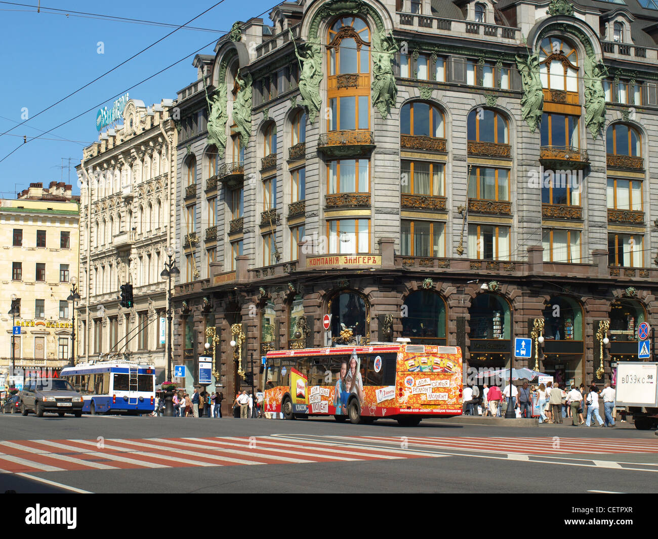 Touristenbusse auf einer Straße in Sankt Petersburg an einem sonnigen Tag mit Straßenbahn Drähten overhead und eine leere Zebrastreifen. Stockfoto