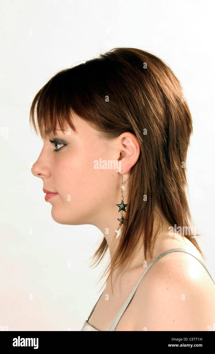 Profil von weiblichen Schulter brünette Haare tragen graue Lidschatten, lange Ohrringe Sterne und Silber satin Weste Top suchen Stockfoto