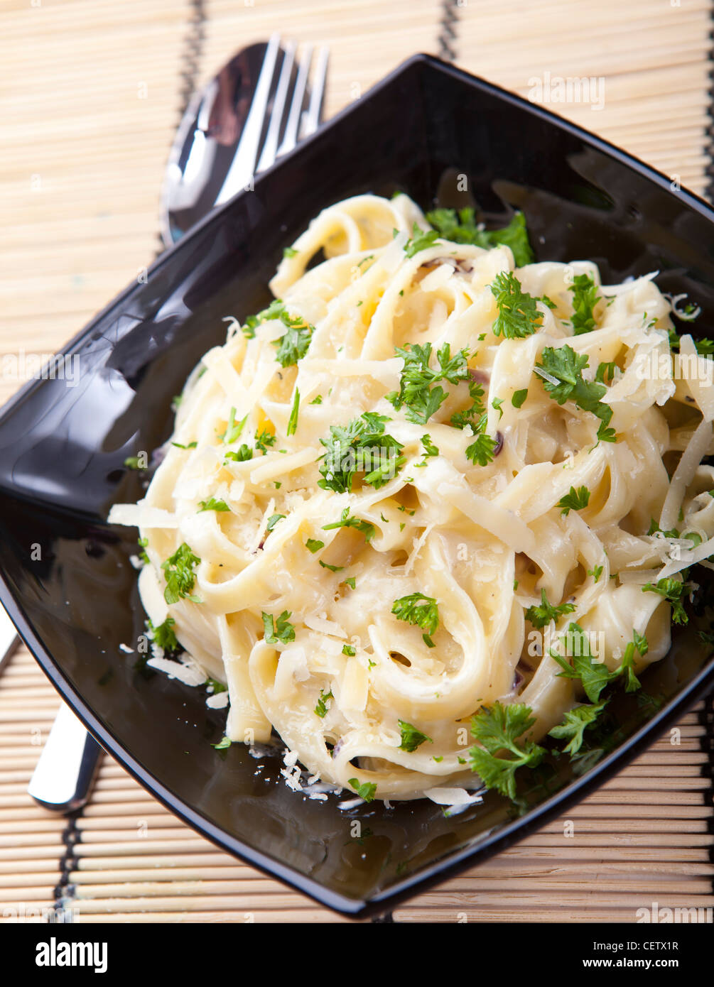 Fettucine Nudeln mit Käse-Sauce in einer schwarzen Schale Stockfoto