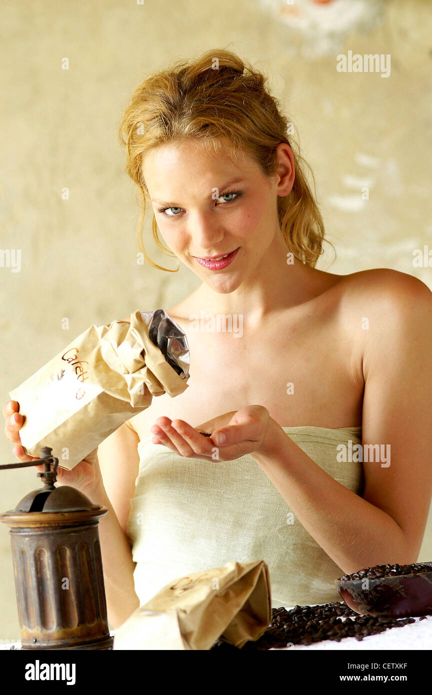 Weibliche blonde lange Haare, Gesicht tragen Leinen umwickelt Körper strömenden Kaffeebohnen aus Tasche in der Hand locker abgebunden Stockfoto