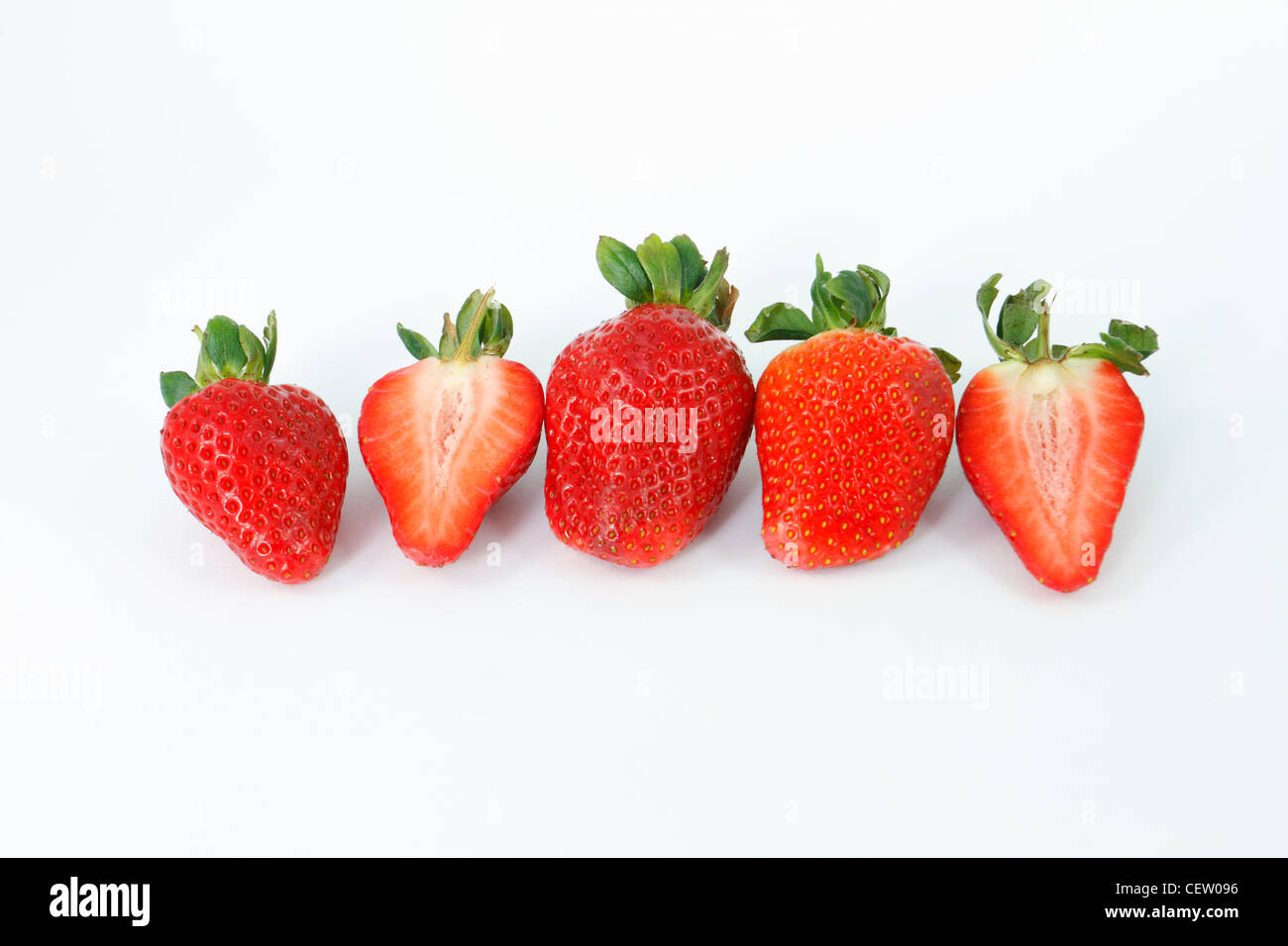 Ganze und halbierte Erdbeeren auf weißem Hintergrund. Stockfoto