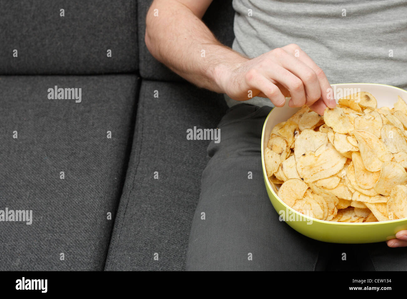 Ein Mann auf einer Couch Potato Chips Essen Stockfoto