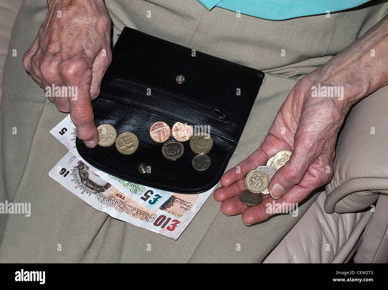 Hände von einer älteren Dame zählen Geld in Sterling Banknoten und Münzen Stockfoto