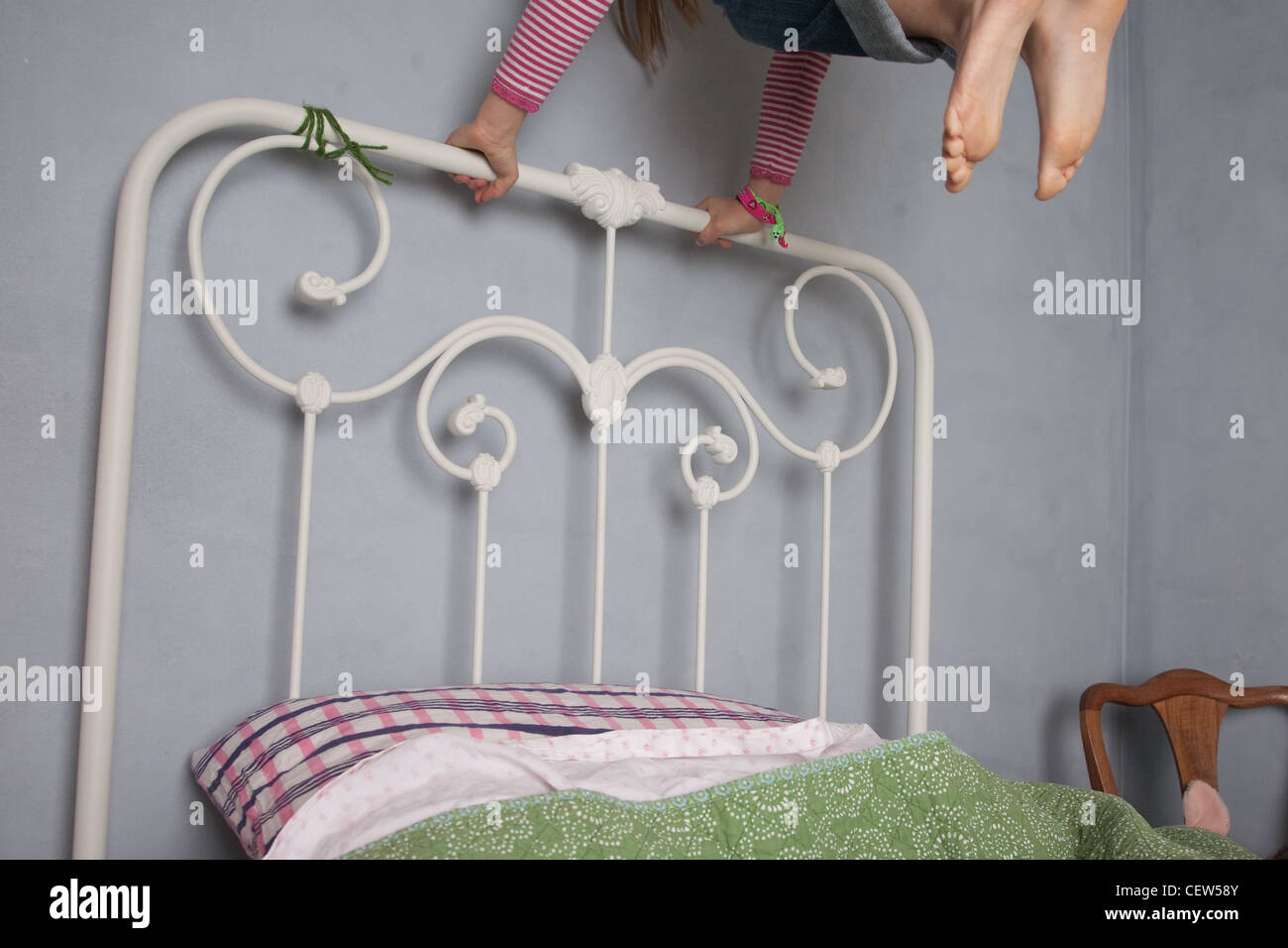 Kind auf Bett springen, zeigt nur die Hände festhalten und Spitzen der Zehen, zu Hause im Schlafzimmer. Stockfoto
