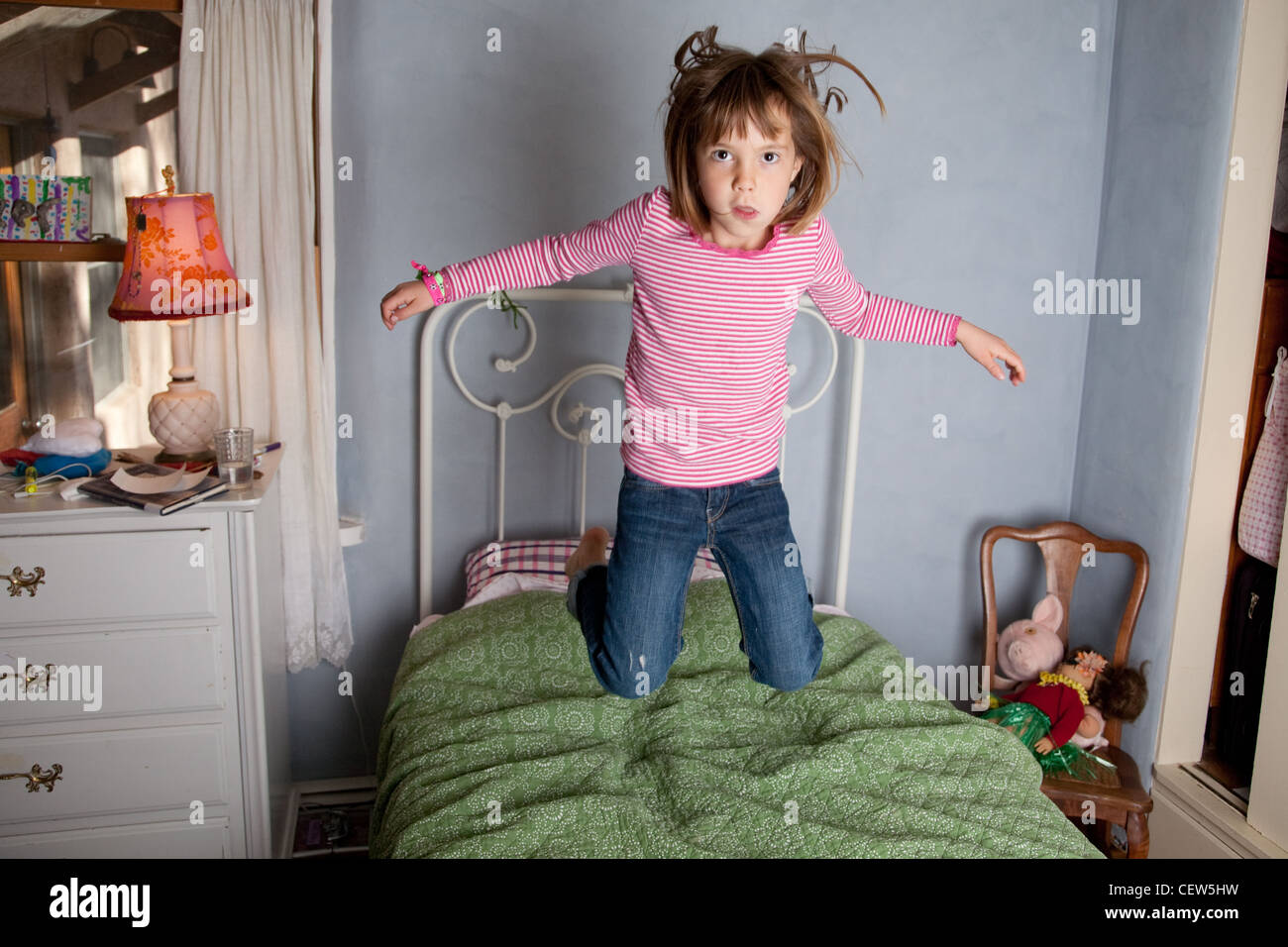 Sechs Jahre altes Mädchen springen auf ihrem Bett. Stockfoto