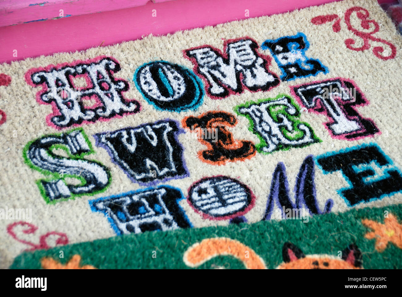 Die Worte "Home Sweet Home" auf einem der mehreren Fußmatten vor einem Geschäft angezeigt Stockfoto