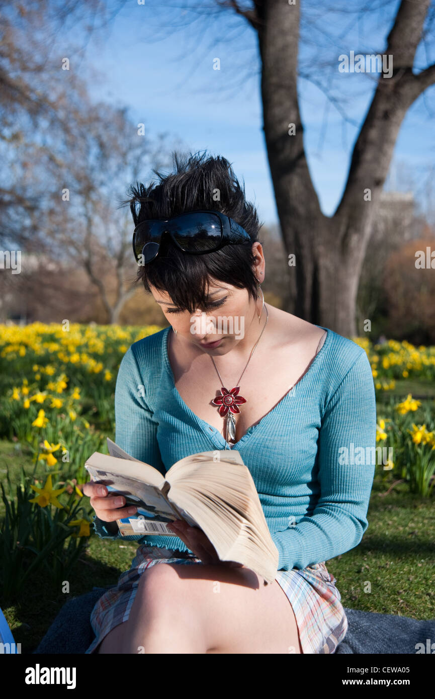 Junge Frau, die ein Buch in St James Park, London, England, Großbritannien, UK Stockfoto