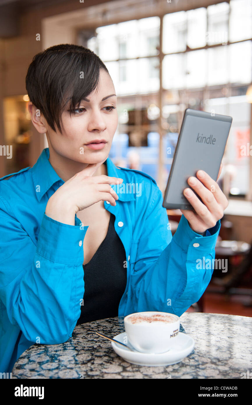 Junge Frau lesen ebook auf eine Amazon Kindle, Großbritannien Stockfoto