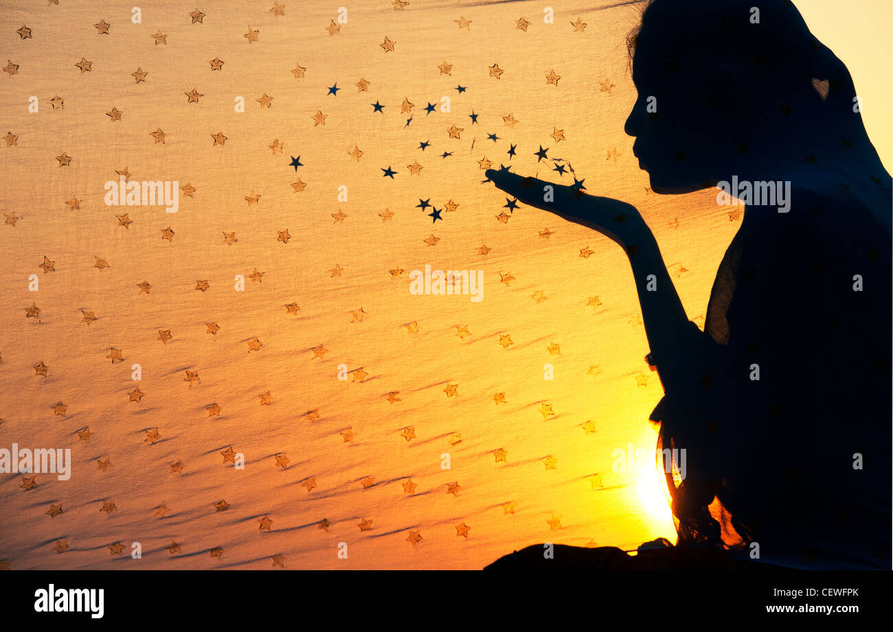 Indische Mädchen hinter einem Sterne Schal Sterne in die Luft bläst. Silhouette Stockfoto