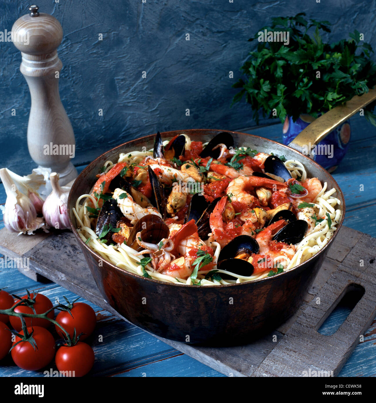 Großen Topf mit Meeresfrüchten Linguine Garnelen, Muscheln und Calamari sitzen an einem grauen Schneidebrett eine Vase mit Blattpetersilie, vine Stockfoto