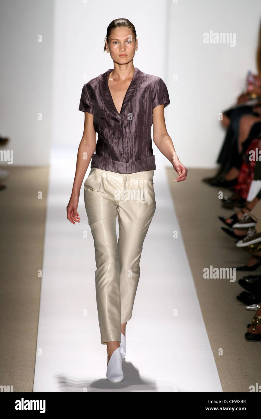 Modellieren, Beige glänzende Hosen und eine lila Kurzarm gefältelt Seidentop mit weißen Schuhen Stockfoto