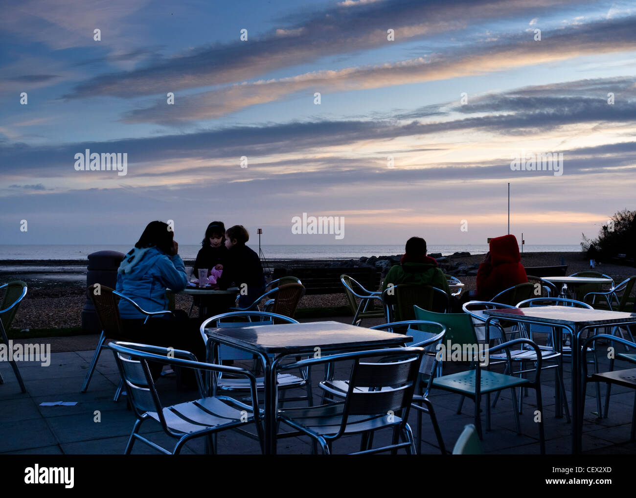 Menschen sich entspannen, trinken Tee und Kaffee den Sonnenuntergang in einem Café am Strand Sussex. Stockfoto