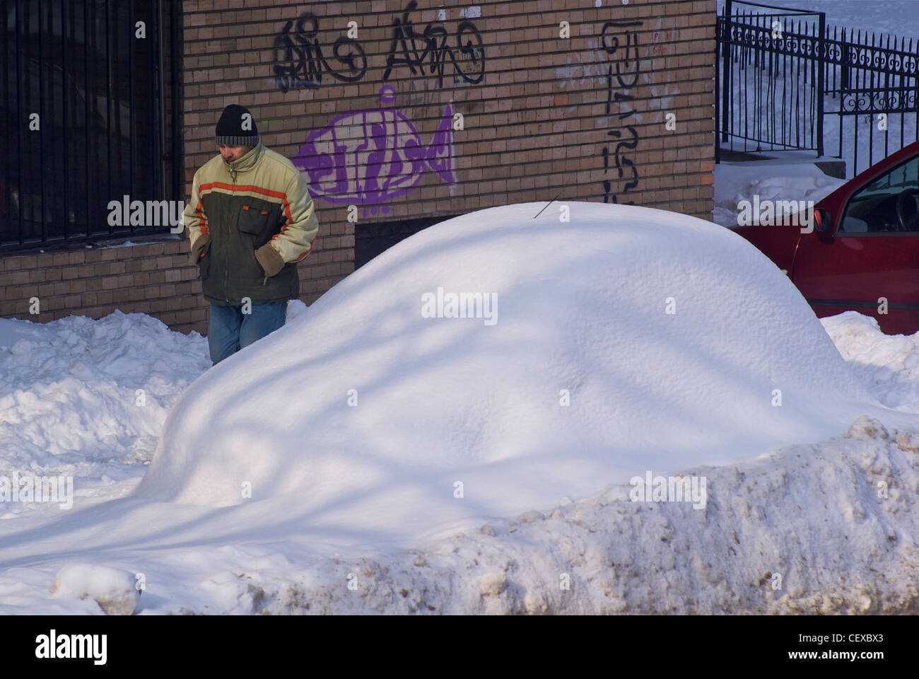 Frau zu Fuß vorbei an ein Auto komplett bedeckt in Schnee