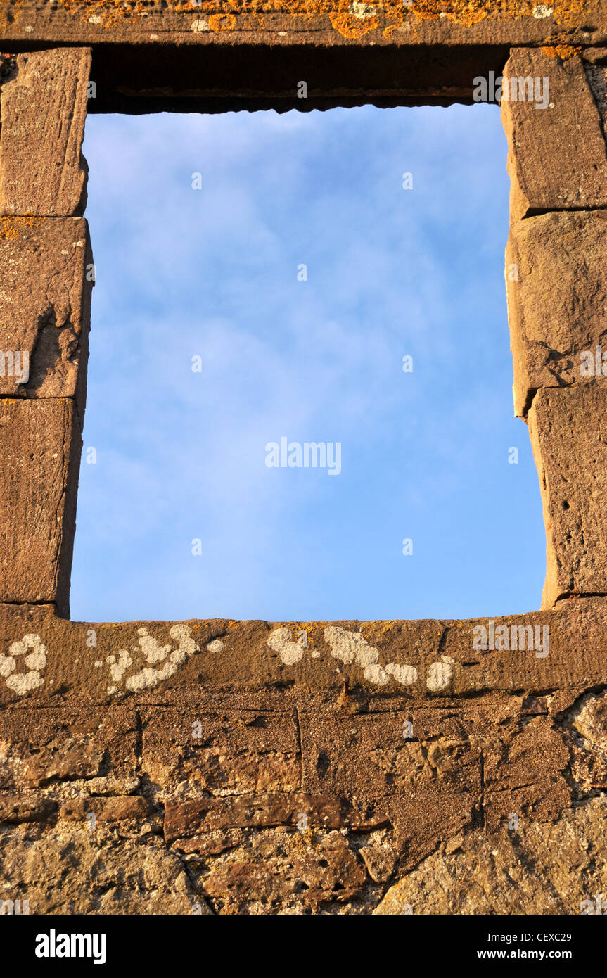 Eine leere Fensterrahmen von einem alten verfallenen Steingebäude enthüllt blauen Himmel über. Stockfoto