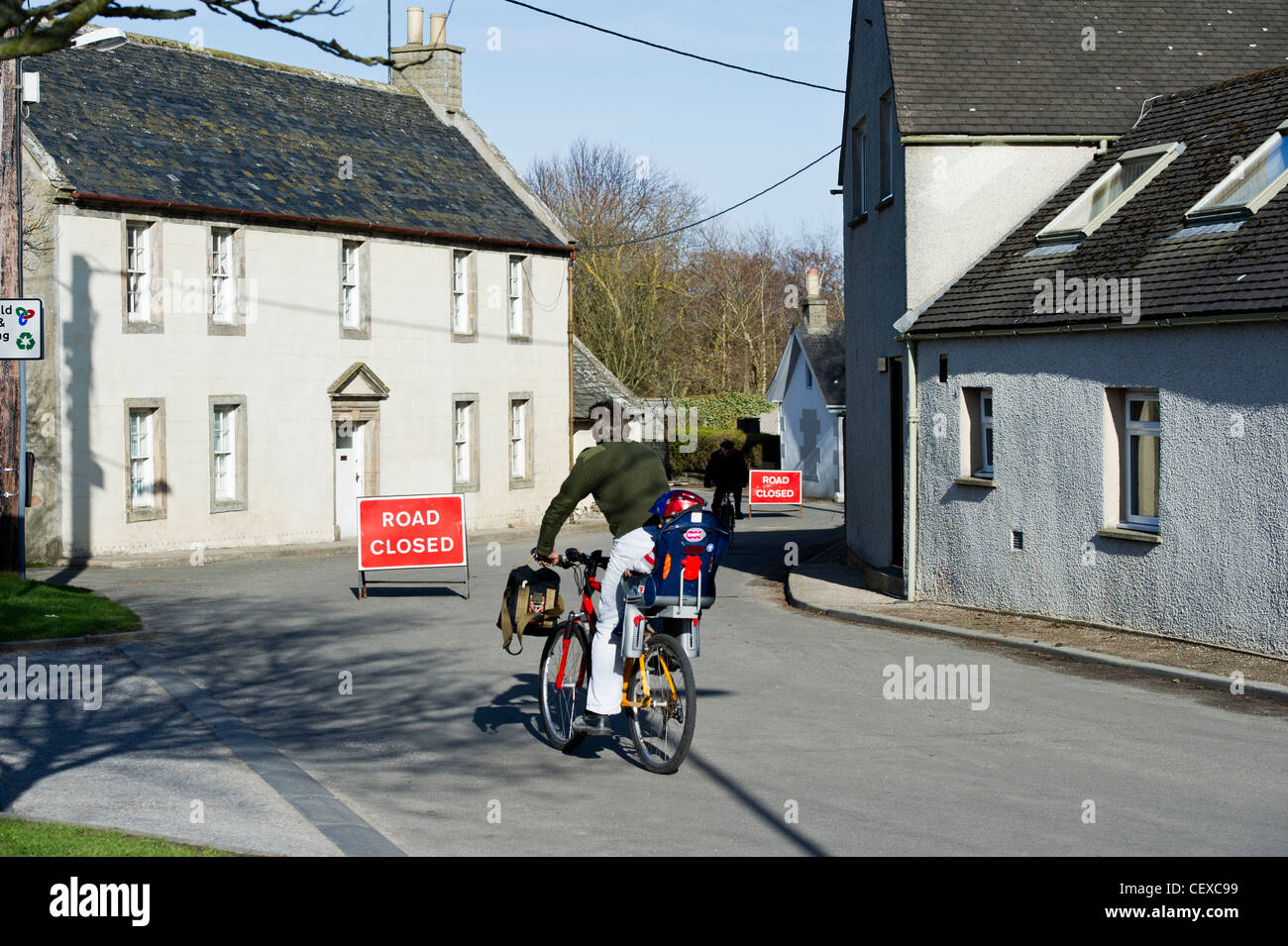 Mann mit Kind reiten vorbei an Straße gesperrt-Schild. Flutung des River Spey in Garmouth, Schottland im April 2010 wegen schweren Schnee schmelzen. Stockfoto