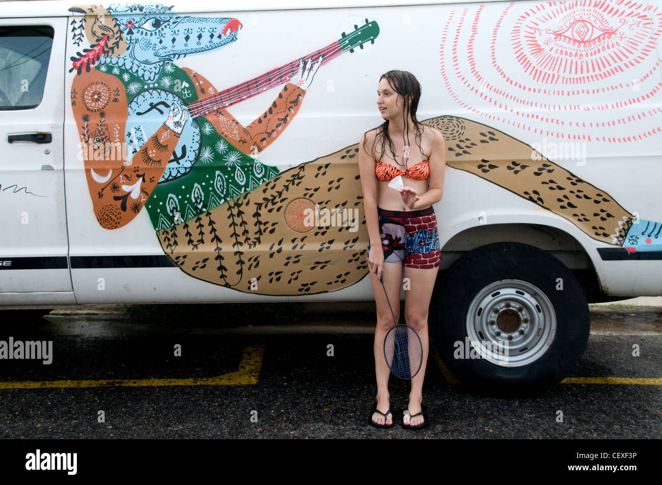 Ein Porträt einer amerikanischen College-Studentin, die sich auf einen weiß dekorierten Van im Viertel Marigny-Bywater in New Orleans, Louisiana, USA stützt. Stockfoto