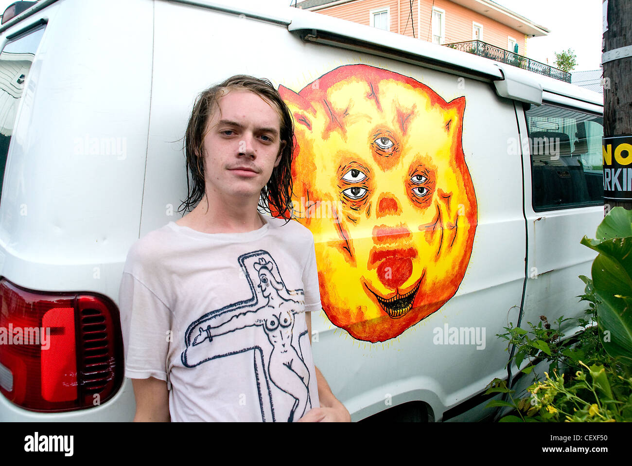 Ein Porträt eines amerikanischen College-Studenten, der sich auf seinen weißen Van im Viertel Marigny-Bywater von New Orleans, Louisiana, USA, stützt. Stockfoto