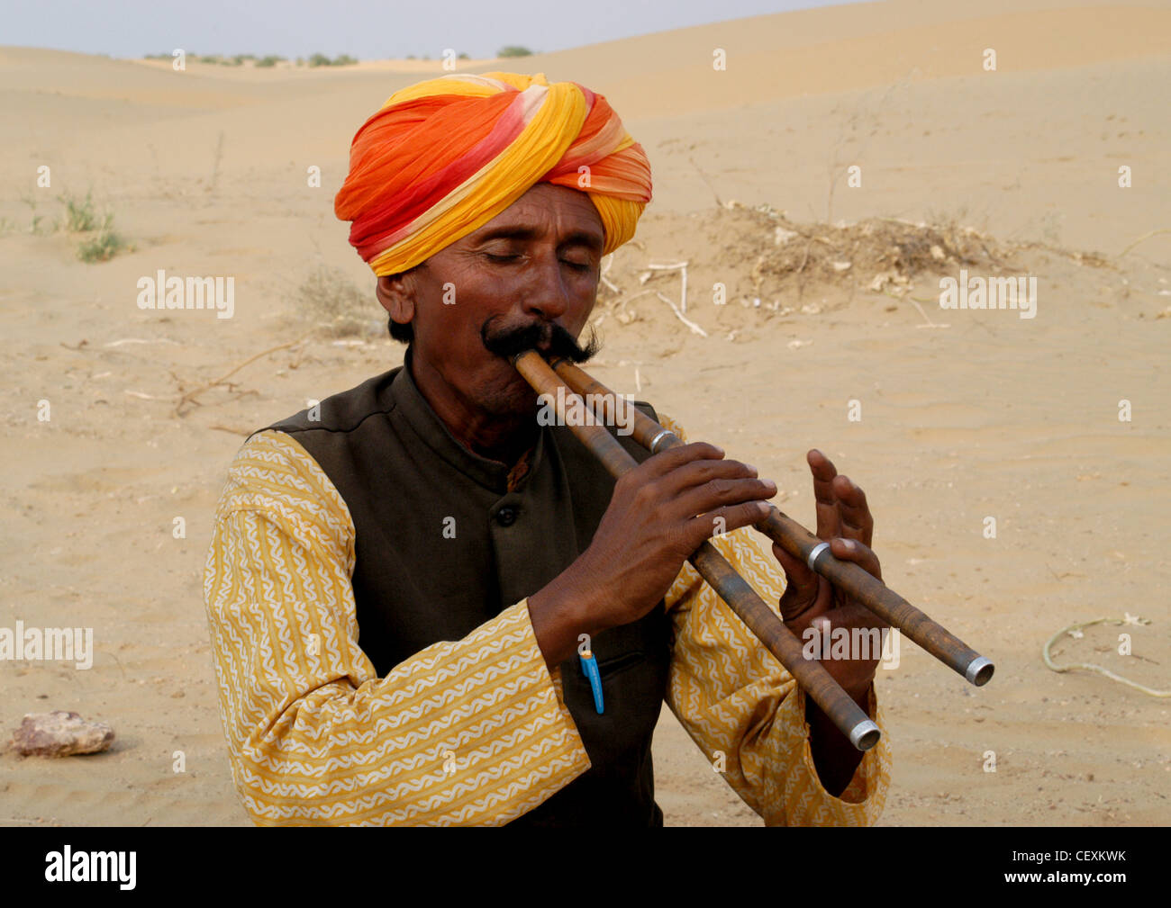 Rajput Mann mit Schnurrbart einzigartige klassische Musik bemerkenswert mit zwei Flöten unterhaltsame Touristen in Rajasthan Wüste. Stockfoto