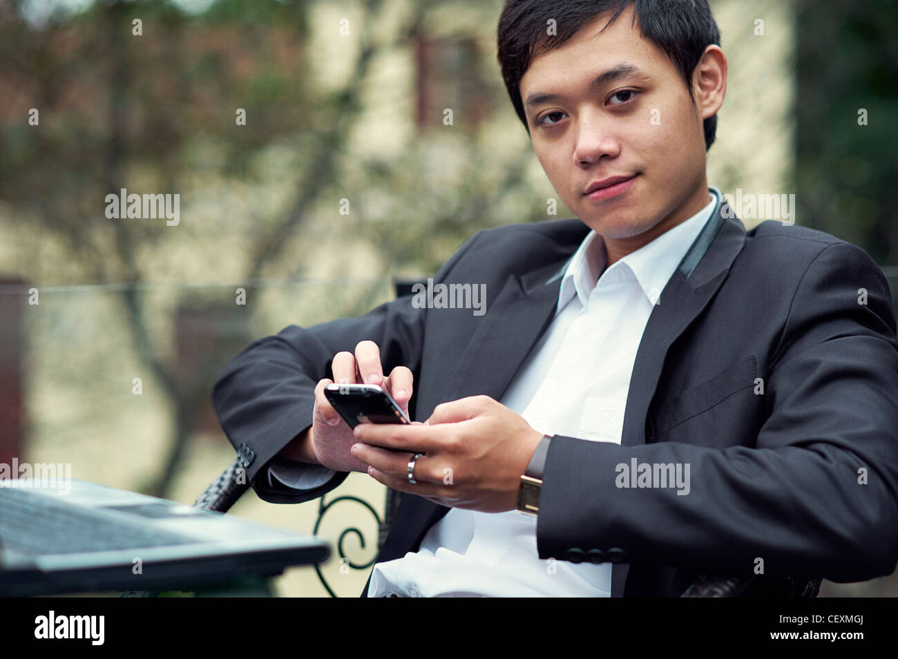 Ein junger Geschäftsmann auf ein Handy in einem Café in Hanoi, Vietnam Stockfoto